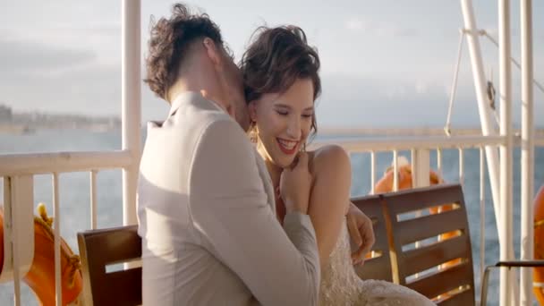 Newlyweds hug on background of cloudy sky. Action. Beautiful newlyweds happily cuddle in cloudy weather. Happy newlyweds in stylish outfits hug in windy weather — Stock Video