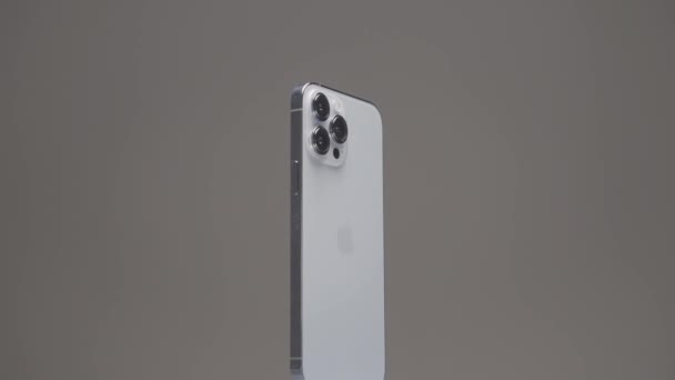 New York - USA, 10.11.2021: закриття нового Iphone 13 pro max з трьома камерами. Почали. Група поширювалася навколо нового срібного смартфона, який повільно обертався ізольованим на бежевому задньому плані.. — стокове відео
