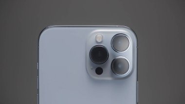 Saint Petersburg - Rusya, 10.11.2021: Yeni iPhone 13 'ün en fazla üç kamerasını kapatın. Başla. Gri duvara karşı yeni gümüş akıllı telefonun şık tasarımı ve profesyonel kameraları.