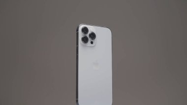New York - ABD, 10.11.2021: Üç kameralı yeni bir Iphone 13 profosyonel yakın çekim. Başla. Buhar bej rengi bir arka planda yavaşça izole edilmiş gümüş bir akıllı telefonun etrafında yayılıyor..