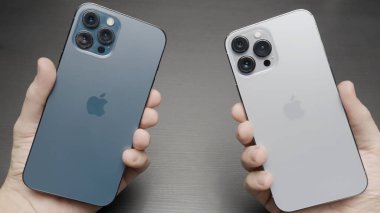 Paris - Fransa, 10.12.2021: erkek el ele tutuşup yeni iPhone 'ları karşılaştırıyor. 13 Pro Max, mavi ve gümüş renkli. Başla. Yeni modern akıllı telefon, pazarlama konsepti ve yeni teknolojiler seçiliyor.