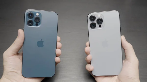 París - Francia, 10.12.2021: manos masculinas sosteniendo y comparando nuevos iPhones 13 Pro Max de colores azul y plata. Acción. Elegir un nuevo smartphone moderno, concepto de marketing y nuevas tecnologías. —  Fotos de Stock