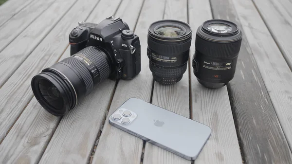 Moskva - Rusko, 10.10.2021: nová kamera Nikon s objektivem a moderním Iphone 13 pro max ležící venku na dřevěném povrchu. Akce. Profesionální vybavení pro fotografování. — Stock fotografie