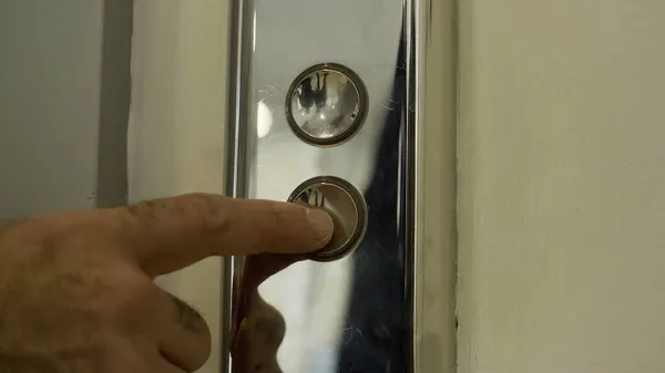 O dedo do homem chega e pressiona o botão do elevador que acende. HDR. Fechar os botões de metal de um elevador público. — Fotografia de Stock