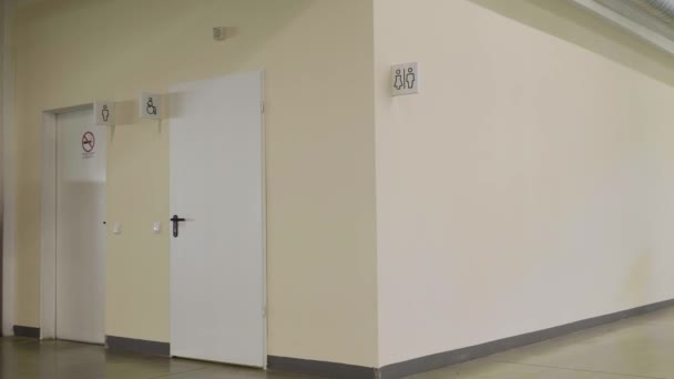 Egy mosdó egy bevásárlóközpontban. HDR-ben. Bézs fal fehér felirattal és férfi és nő sziluettjeivel a nyilvános WC-ben. — Stock videók
