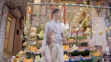 Bazaar 'ın arka planında bir çift. Başla. Zarif bir çift meyve tezgahının arka planında duruyor. Manavda poz veren güzel bir çift.