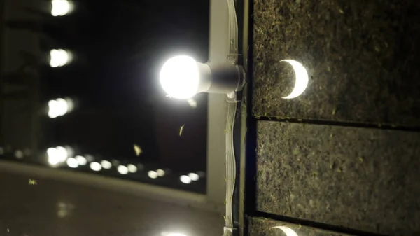 Las mariposas acuden a la bombilla ardiente. HDR. Acercamiento de polillas y moscas vuelan cerca de la lámpara en una pared del edificio por la noche. —  Fotos de Stock