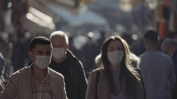 Люди носят хирургические маски на уличном рынке. Начали. Толпа людей в медицинских масках на лицах, идущих вдоль различных товаров на уличном рынке. — стоковое фото