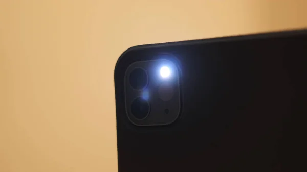 Primo piano di uno smartphone che scatta una foto con un flash isolato su sfondo giallo. Concetto. Flash lampeggiante sul retro di un cellulare moderno. — Foto Stock