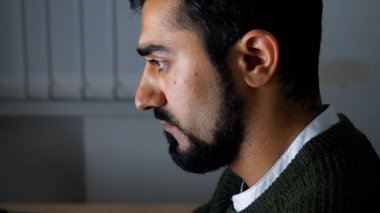 Dizüstü bilgisayarla çalışan sakallı bir gencin yan görüntüsü. HDR. Ofis çalışanı masasında oturuyor ve ekrana bakıyor..