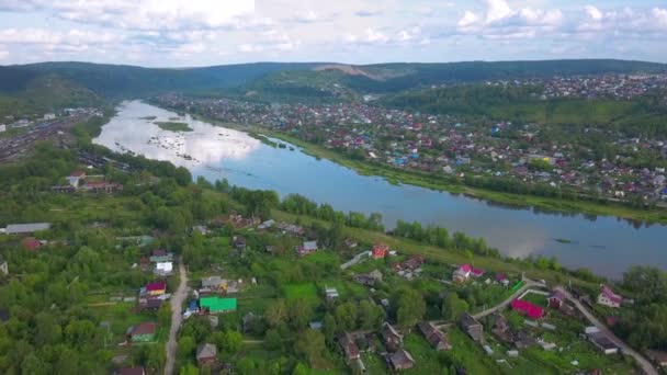 Het uitzicht vanaf de drone. Een knip. Prachtig zomers uitzicht op het blauwe meer, huizen, bergen en blauwe lucht. — Stockvideo