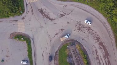 Helikopterden görüntü. Şarjör. Yeşil parkın yanında arabaların olduğu virajlı bir yol manzarası ve park yeri olan bir üs.
