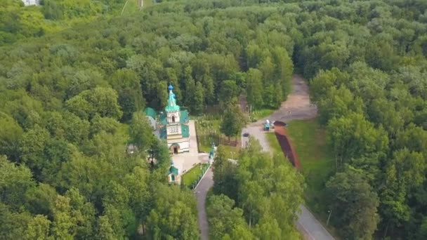 Birds-eye view. Clip. A beautiful green forest with a monastery in the middle . There are also some roads and some places of the city in the background. — Stock Video