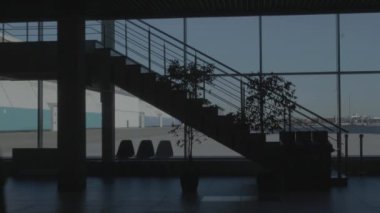 Bir iş merkezinin penceresinin arkasında gün batımı gökyüzü. HDR. İş merkezinin içinde yürüyen insanlar ya da içi bitki ve merdivenlerle dekore edilmiş bir alışveriş merkezi..