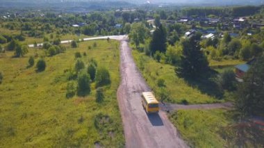 Kuş bakışı görüş. Şarjör. Sarı bir otobüsün yeşil ağaçların ve çimenlerin olduğu uzun bir yol.