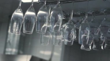 Mutfak restoranında baş aşağı asılı duran bardakları kapat. HDR. Beyaz duvarlarda ve tavan arkaplanında şeffaf şarap ve kokteyl bardakları var..