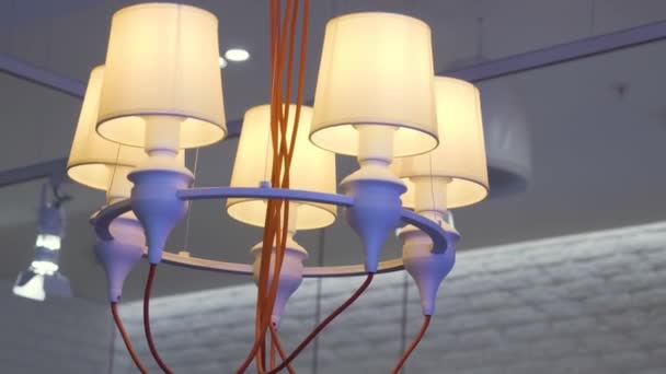 Primo piano del lampadario appeso su sfondo bianco soffitto. HDR. Lampada a sospensione insolita con fili arancioni, bordo metallico viola e apparecchi beige. — Video Stock