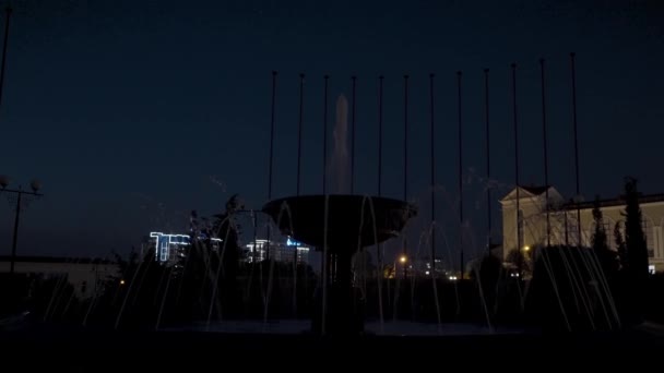 Paisaje nocturno de la ciudad con el hermoso edificio administrativo y una fuente sobre fondo de cielo azul oscuro. Acción. Concepto de arquitectura. — Vídeos de Stock