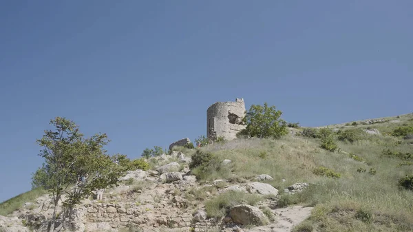 Стародавній зруйнований замок на вершині пагорба на синьому чистому фоні неба. Дія. Розбита покинута кам'яна будівля на зеленому полі . — стокове фото