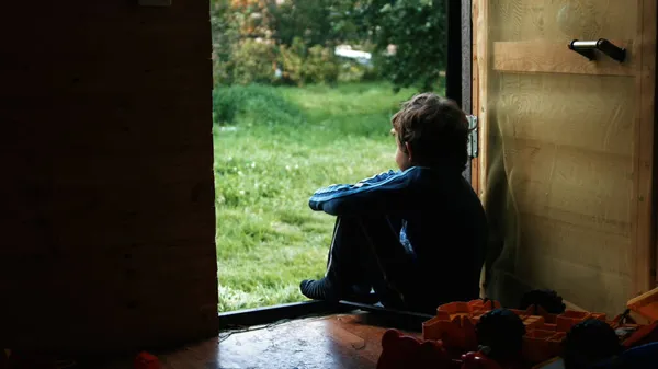Siedzący chłopiec. Kreatywny. Mały chłopiec, który patrzy na zieloną ulicę obok swoich zabawek w pokoju. — Zdjęcie stockowe