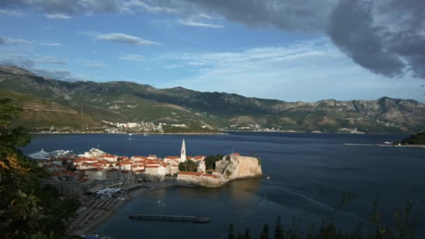 Hermoso paisaje de un dron. Creativo. El mar, frente al cual hay grandes montañas verdes, casas blancas y un camino cercano, y un cielo gris nublado. — Vídeo de stock