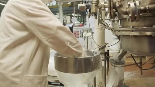 Productie. Een knip. Werken in een fabriek waar een werknemer in witte speciale kleding werkt met ijzer apparatuur. — Stockvideo