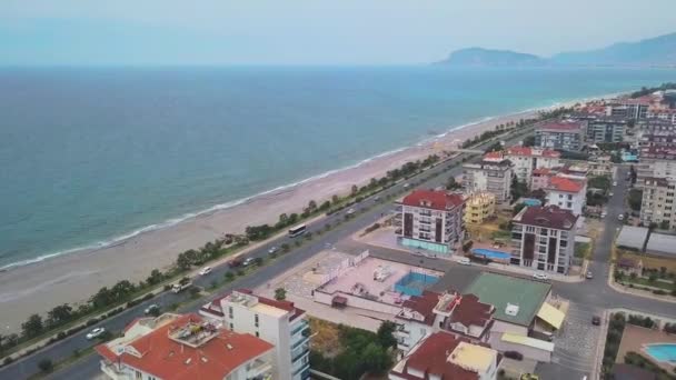 La vista dal drone. Clip. La distesa del mare con la spiaggia, accanto alla strada con le auto e anche un piccolo pezzo di città con grandi case. — Video Stock