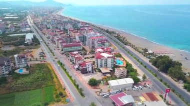 İnsansız hava aracından güzel bir manzara. Güzel bir okyanus ve yolu olan büyük evler görebilirsiniz. Arkadan güzel yeşil dağlar görebilirsiniz..