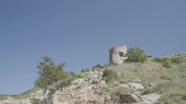 Tepedeki eski harabe şato, açık mavi gökyüzü arka planında. Başla. Yeşil alanda terk edilmiş bir taş bina..