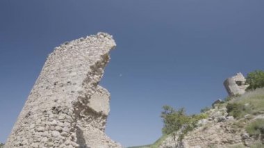 Tepedeki eski harabe şato, açık mavi gökyüzü arka planında. Başla. Yeşil alanda terk edilmiş bir taş bina..