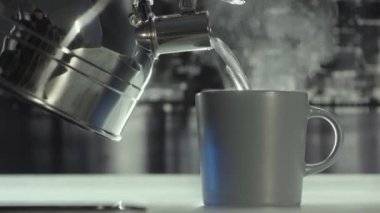Cilalanmış çelik gaz ısıtıcısından bardağa sıcak su dök. Başla. Evdeki gri renklerle mutfaktaki rahat atmosfer..
