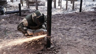 Bakım. Şarjör. Özel maskeli ve elbiseli bir adam ormanda kaynakçı gibi çalışır..