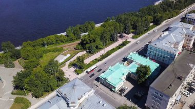 İnsansız hava aracının görüntüsü. Clip. Nehri görebileceğin güzel bir şehir merkezi, küçük bir park ve arabalı bir yol.