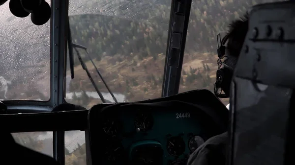 De piloot vliegt in een helikopter. Een knip. Een man bestuurt een helikopter tegen de achtergrond van een bos.. — Stockfoto