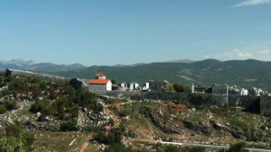 Manzaranın güzel bir kuş bakışı görüntüsü. Yaratıcı. Eski binaların ve evlerin yanında yüksek dağ sıraları ve küçük beyaz bulutlu mavi bir gökyüzü..
