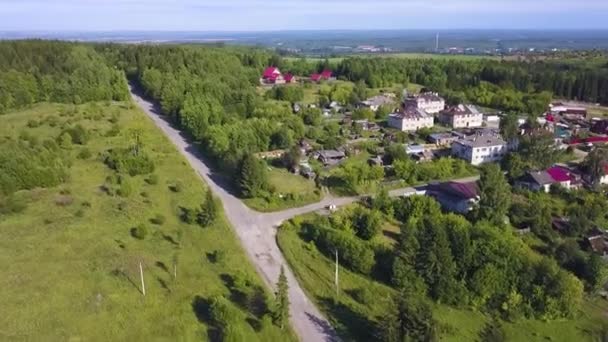 Beautiful view from the helicopter . Clip. A beautiful green summer road near the city, with small residential buildings and a beautiful landscape of forests, mountains and misty fields. — Stock Video