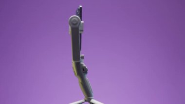 Rusya - Moskova, 11.25.2021: işlevsel tripodda yeni akıllı telefonlara yakın çekim. Başla. Leylak duvar arka planında dengeleyiciyle dönen üç kameralı yeni profesyonel telefon..