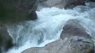 Kocaman bir su jeti. Şarjör. Gri büyük taşlara vuran berrak soğuk su .