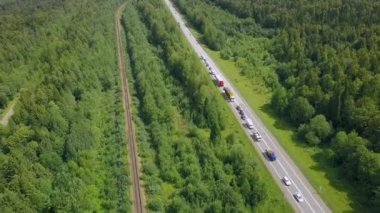 Arabalarla dolu kocaman bir otoyol. Şarjör. Pist yeşil bir yaz ormanının arka planında ve yaz günü kocaman ağaçlar var..