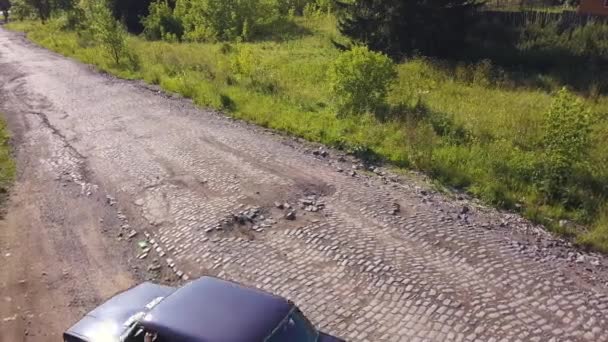 Zielona letnia droga. Klip. Szary asfalt z małymi kamieniami i roślinnością z rosyjskim samochodem, który dryfuje — Wideo stockowe