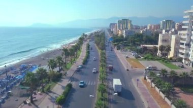 İnsansız hava aracı. Şarjör. Güzel bir okyanusun üzerinde uçmak ve plajı, arabaları, trafik sıkışıklığı ve büyük evleri olan büyük bir tatil köyü.