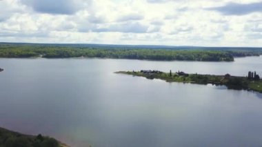 İnsansız hava aracının görüntüsü. Şarjör. Arka planda büyük, berrak bir göl var. Büyük, yeşil bir orman ve sakin bir gökyüzü..