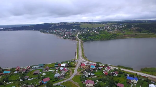 Letní pohled z dronu. Klip. Pohled na malé městečko s řekou, most přes rybník s auty, okolní parky, lesy a domy a mírně zatažená obloha. — Stock fotografie