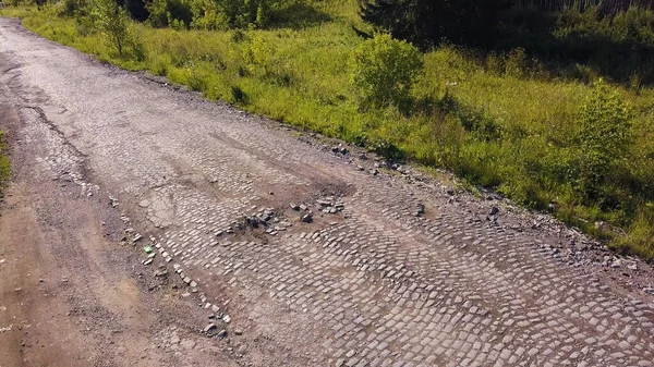 Zöld nyári út. Csípés. Szürke aszfalt kis kövekkel és növényzettel egy orosz autóval, ami sodródik — Stock Fotó