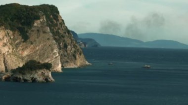 Güzel kuş bakışı manzara. Yaratıcı. Üzerinde turuncu bir sürat teknesi olan büyük mavi bir deniz ve büyük yeşil bir dağ görünür ve mavi bir gökyüzü.
