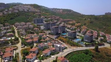 Helikopterden manzaraya bak. Clip. Otellerin, yeşil parkların, spor sahalarının ve arka planda büyük yeşil dağların olduğu güzel bir tatil köyü.