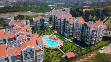 Kuş bakışı görüş. Şarjör. Çevresindeki yeşil parkların ve arka plandaki dağların yanında yüzme havuzu olan bir yazlık yer..