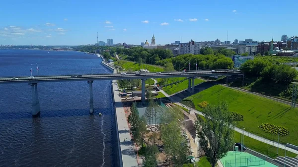 La vista dal drone. Clip. Un enorme ponte che attraversa il fiume con auto accanto al parco e grandi case. — Foto Stock