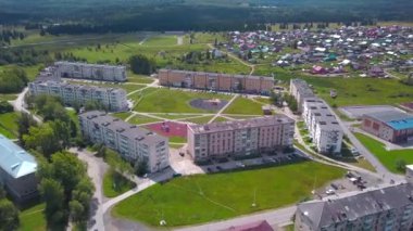 Helikopterin yüksekliğinden bak. Şarjör. Büyük ağaçların ve parkların yanında küçük evler ve birkaç arabanın geçtiği bir yol.