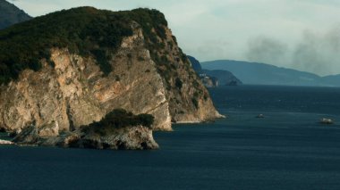 Güzel kuş bakışı manzara. Yaratıcı. Üzerinde turuncu bir sürat teknesi olan büyük mavi bir deniz ve büyük yeşil bir dağ görünür ve mavi bir gökyüzü.